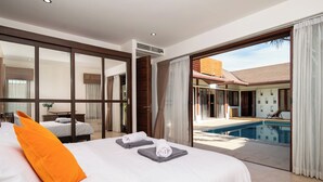 Una camera d'albergo moderna con un letto grande, vista su una piscina esterna e una porta scorrevole con accesso a un balcone.