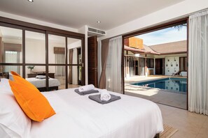 Ein modernes Hotelzimmer mit einem großen Bett, Blick auf einen Außenpool und einer Schiebetür zum Balkon.