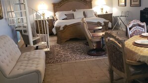 Quarto com cama, cadeira, mesinha, abajur e escada.