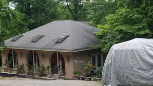 Uma casa com telhado inclinado, varanda coberta e entrada com calçamento de brita.