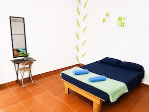 Ein Zimmer mit Bett, Schreibtisch, Stuhl, Spiegel und Wandbildern.