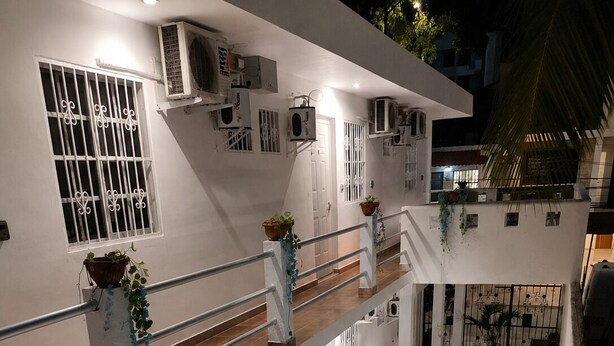 Een gebouw met meerdere verdiepingen, balkons, airconditioning en buiten zitplaatsen.