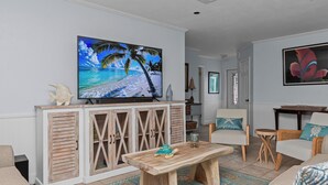 Ein Wohnzimmer mit Fernseher, Holzschrank und Esstisch.