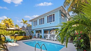Ein zweistöckiges Haus mit Swimmingpool, überdachter Terrasse und weißem Zaun.