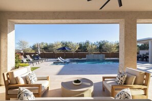 Un área de piscina con sillones reclinables, un jacuzzi y una terraza con asientos.