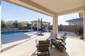 Un patio cubierto con piscina, mobiliario exterior y una pérgola.