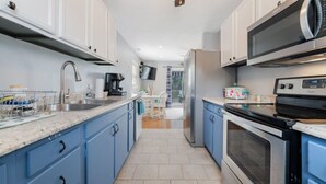 Une cuisine moderne avec des meubles bleus, un évier en acier inoxydable, un four à micro-ondes et une cuisinière.