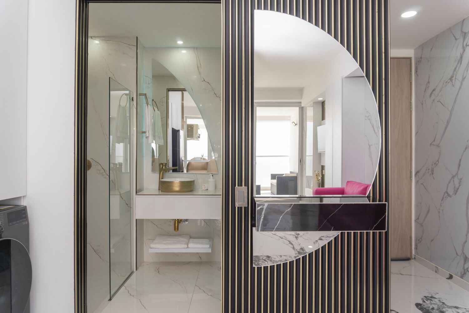 A modern bathroom with a glass partition, a vanity with a gold sink, and a large mirror.