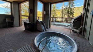 A covered outdoor swimming pool with a metal ladder, surrounded by brick flooring and wooden deck. - Keystone Mountain Escape (Keystone)