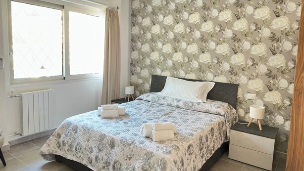 A bedroom with a large bed, floral wallpaper, a radiator, a window with curtains, and bedside lamps. - A Room with private bathroom; Sweet Home Fleming (Roma)