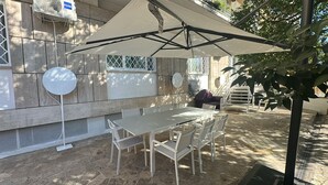 An outdoor patio with a table and chairs, a large umbrella, and a building with stone walls and windows. - A Room with private bathroom; Sweet Home Fleming (Roma)