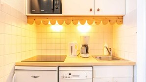 Eine kleine Küche mit Mikrowelle, Kaffeemaschine und Geschirrspüler.