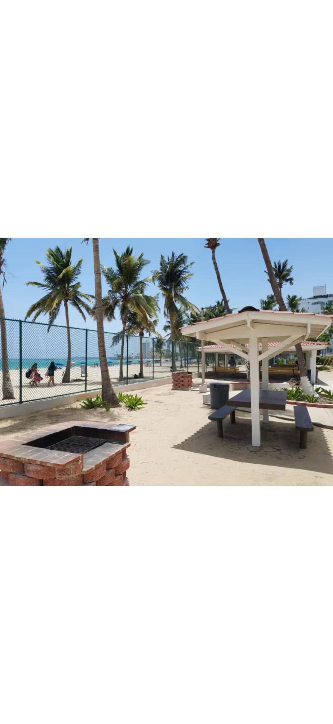 A beachside patio with a grill, seating, and a covered area.