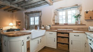 Una cocina con armarios blancos, encimera de madera, un lavamanos, una ventana y una estufa.
