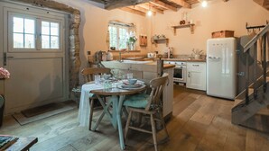 Una cocina rústica con comedor, vigas de madera y un refrigerador blanco.