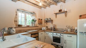 Una cocina con encimera de madera, electrodomésticos blancos y ventana con vistas.