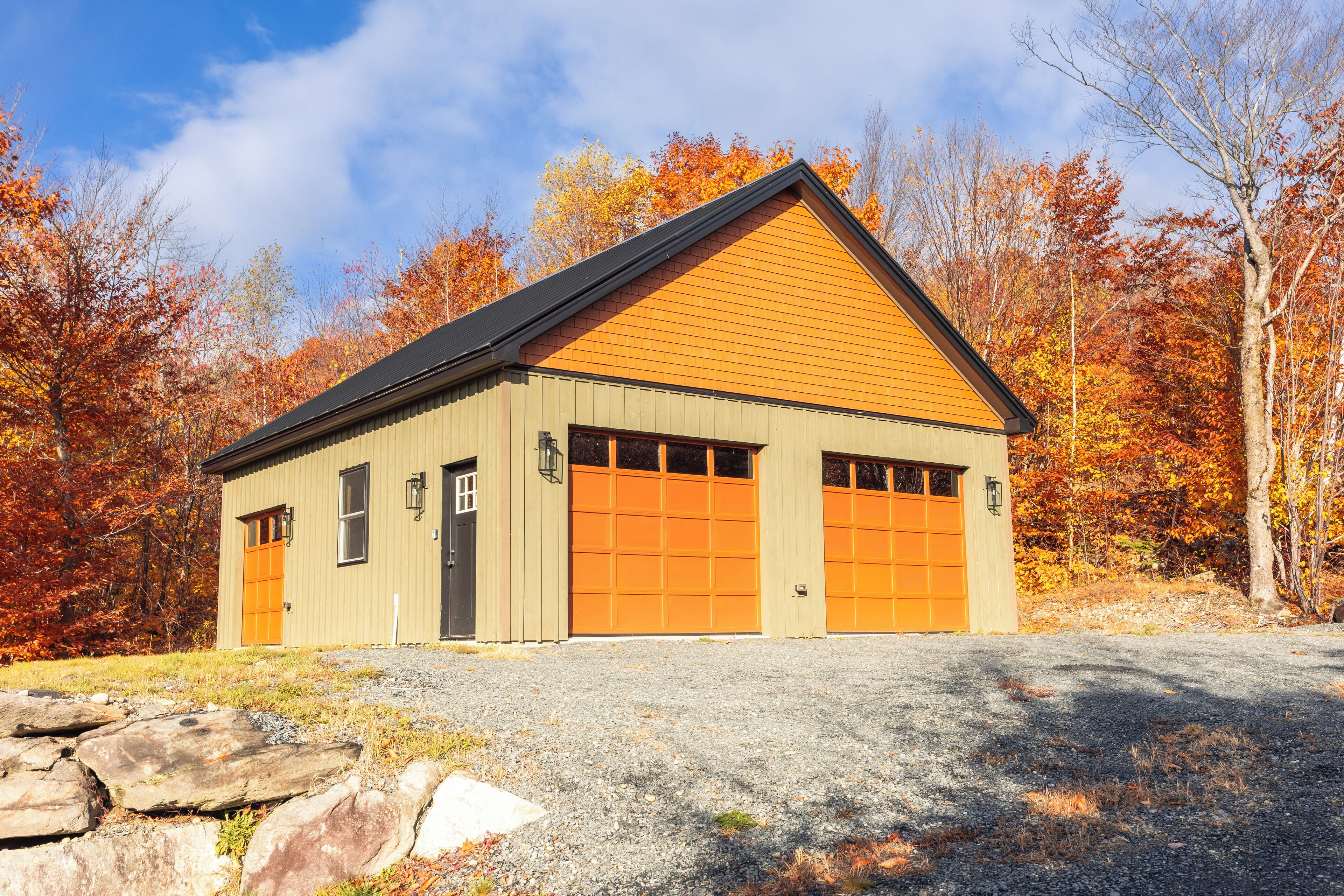A single-story building with a gabled roof, two garage doors, and a small porch area.