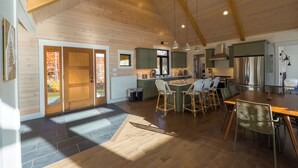 A spacious kitchen with wooden beams, a central island with bar stools, and a large refrigerator. - Mountain Escape - Views • Firepit • Near Sugarloaf (Kingfield)