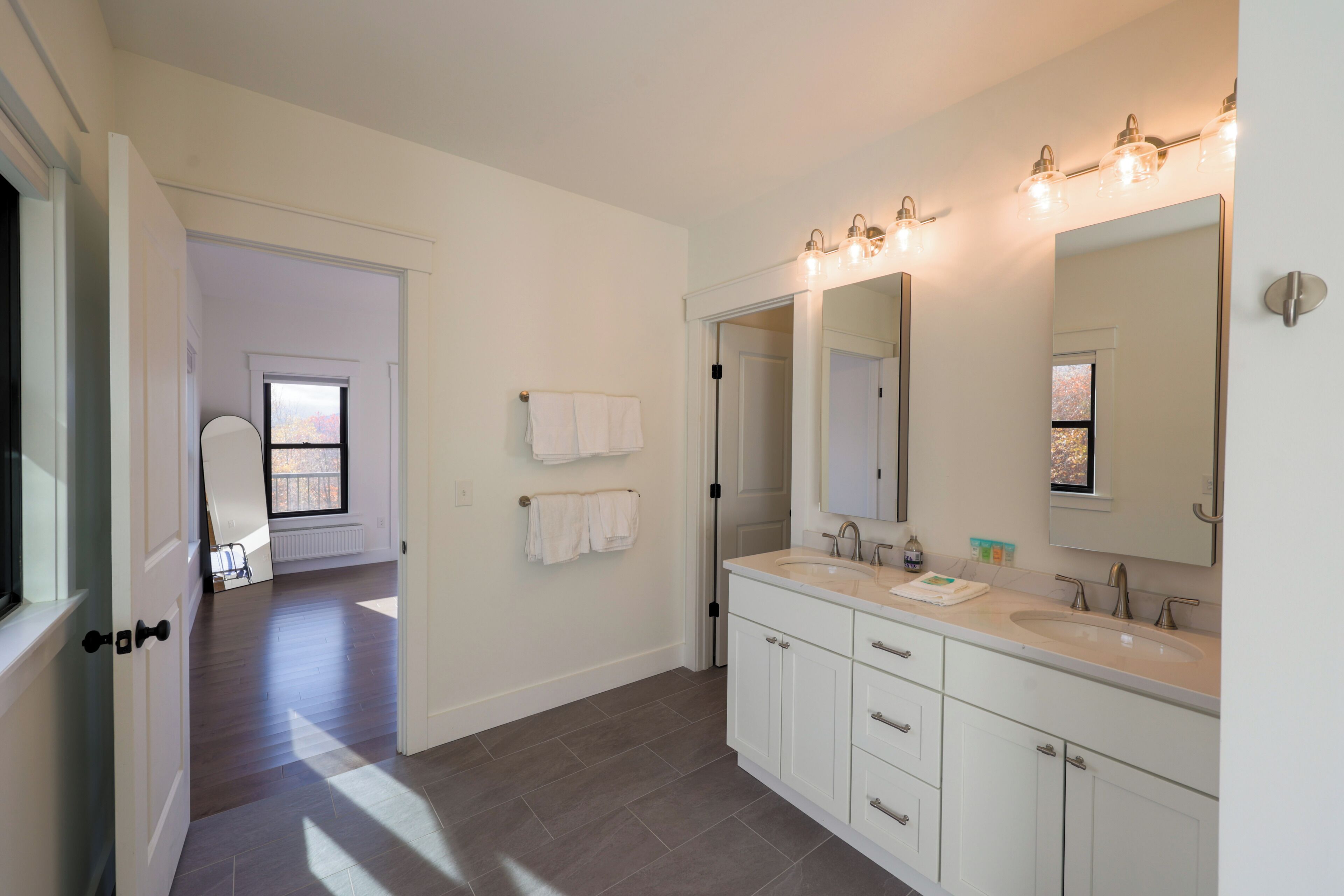 A modern bathroom with a double sink, a large mirror, and a walk-in shower.