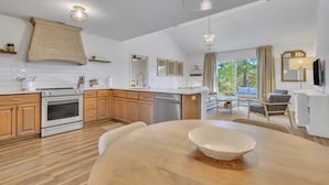 A modern kitchen with wooden cabinets, a built-in oven, and a dining area with a large table and chairs.