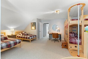 Une chambre avec deux lits simples, un bureau, une chaise et un lit superposé.