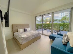 A bedroom with a bed, a blue sofa, and a balcony with a table and chairs. - Azure Aruba-3BR Resort Style Villa by Eagle Beach (Oranjestad)