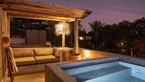 A rooftop terrace with a hot tub, seating area, and a hanging light fixture. - Pousada Zinga Caraíva (Porto Seguro)