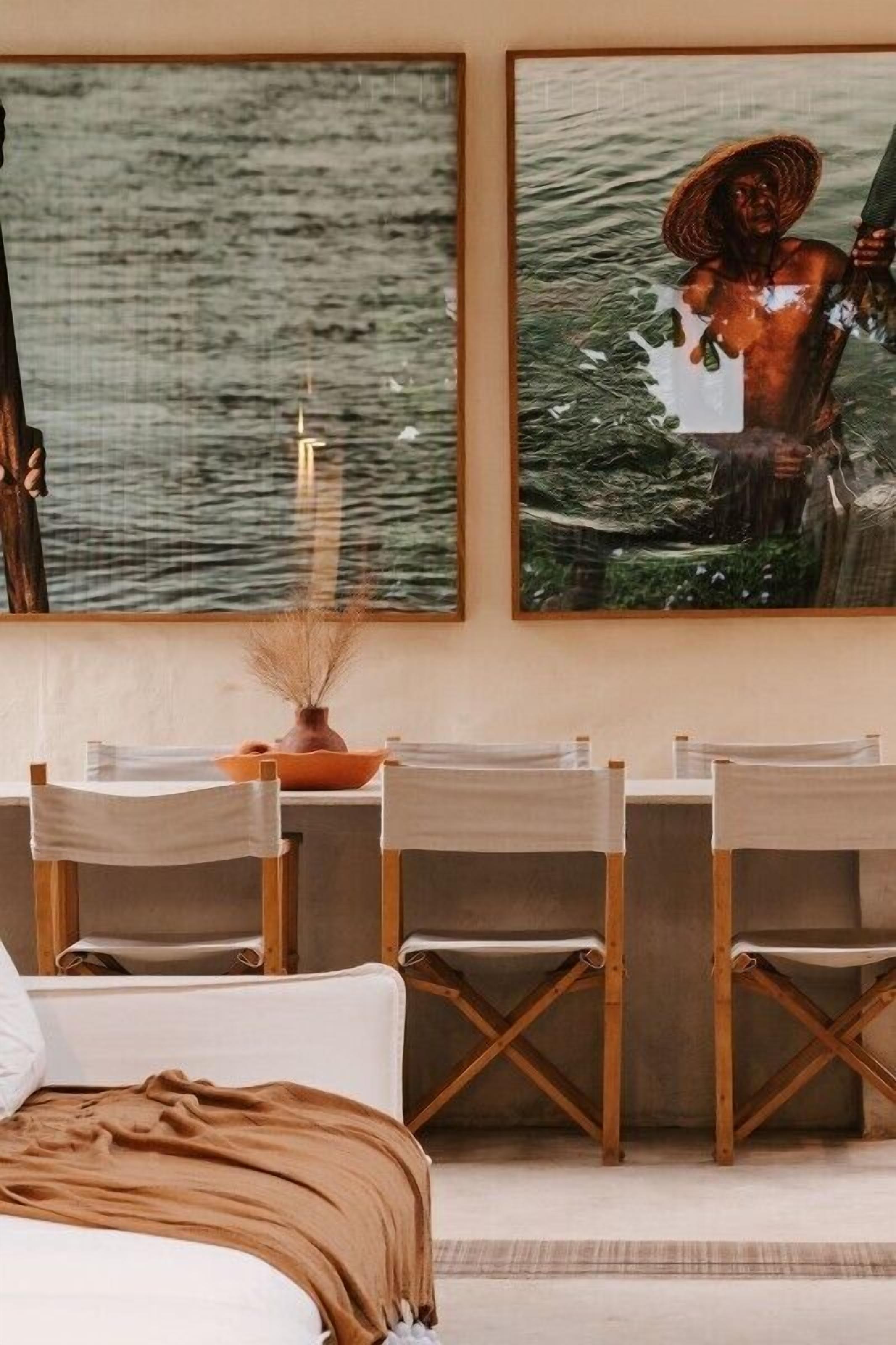 Una stanza con un letto, un tavolo da pranzo con sedie e due opere d'arte appese alla parete.