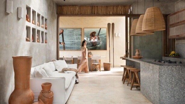 A modern interior with a white sofa, a dining area, and a kitchen with a large window. - Pousada Zinga Caraíva (Porto Seguro)