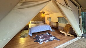 Eine gemütliche Zeltdominik mit einem Einzelbett, Holzboden und einem Kuhfellteppich.
