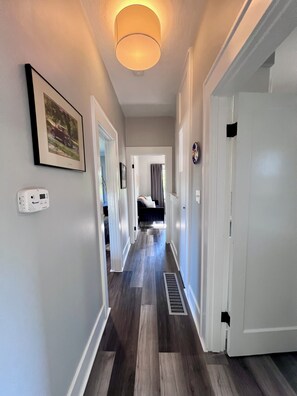 A hallway with a ceiling light, a framed picture, a thermostat, and a door. - Green Lake · 3BR + Office · Sleeps 6 · Near Light Rail Station, Freeway & Bus (Seattle)