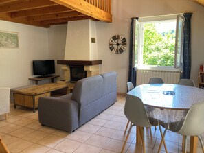 Un salon confortable avec une cheminée, un canapé, un téléviseur et une table à manger avec des chaises.