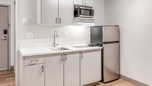 A modern kitchen with white cabinetry, a stainless steel refrigerator, and a microwave. - Aspen Suites Hotel Fairbanks (Fairbanks)