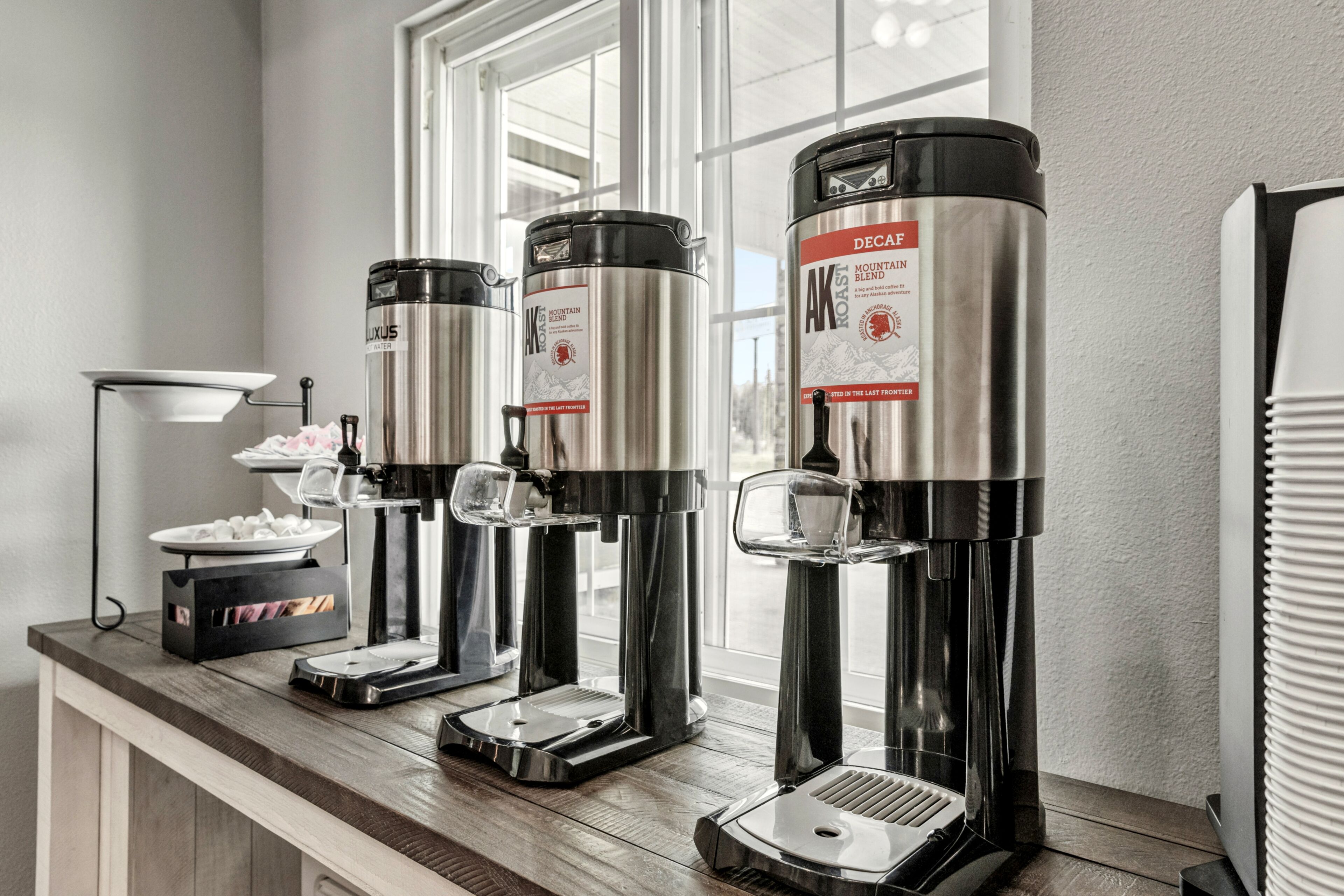 Een koffiehoek met vier koffieautomaten, elk met een roestvrijstalen behuizing en een glazen kan.