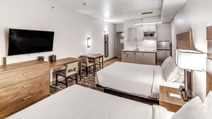 A hotel room with two beds, a desk, a television, a kitchenette, and a bathroom. - Aspen Suites Hotel Fairbanks (Fairbanks)