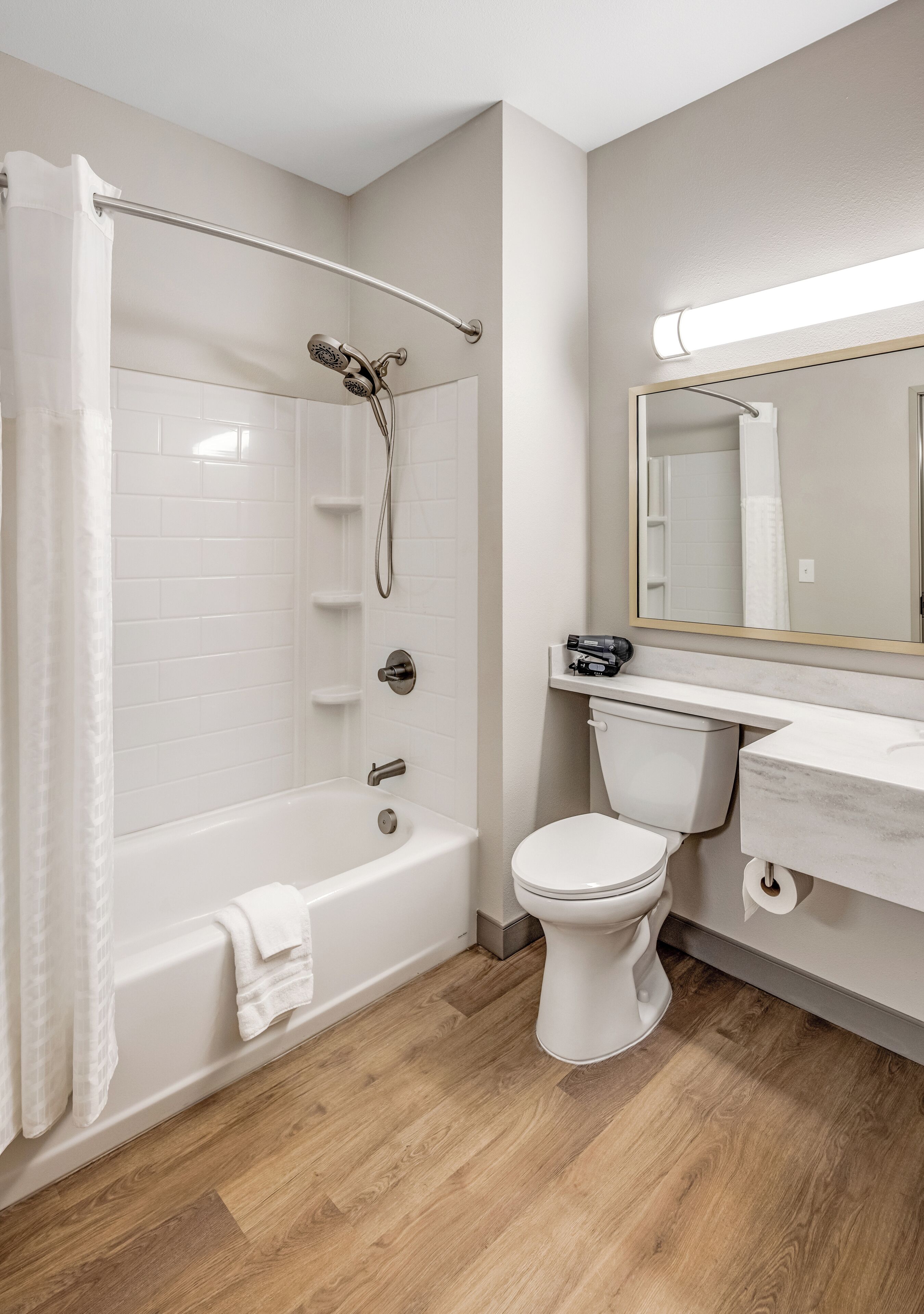 A modern bathroom with a bathtub, shower, toilet, and vanity.