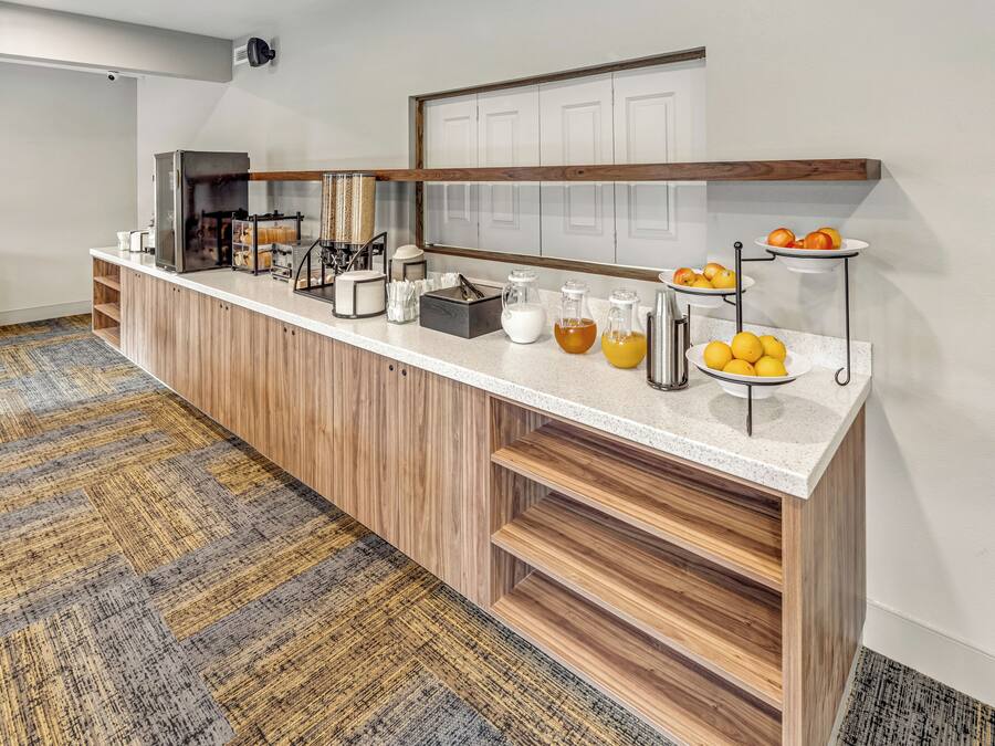 Un comptoir pour le petit-déjeuner équipé d’une machine à café, de distributeurs de jus et d’un présentoir à fruits.