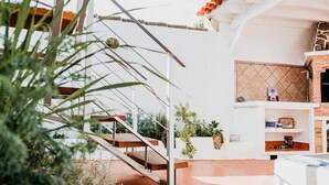 A staircase leading to a balcony with a view of the outdoors, a brick fireplace, and a shelf with various items.