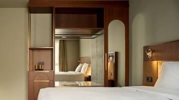 Une chambre d’hôtel avec un grand lit, une armoire en bois, un miroir et une petite table avec une lampe.