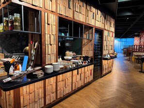 A restaurant interior with brick walls, a long counter with various food items, and a wooden floor. - Skald Akureyri, Curio Collection by Hilton (Akureyri)