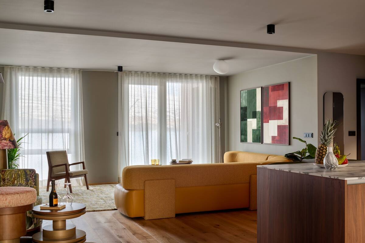A modern living room with a sofa, a coffee table, a chair, and a dining area.