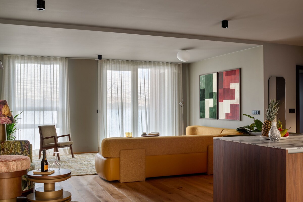 A modern living room with a sofa, a coffee table, a chair, and a dining area.