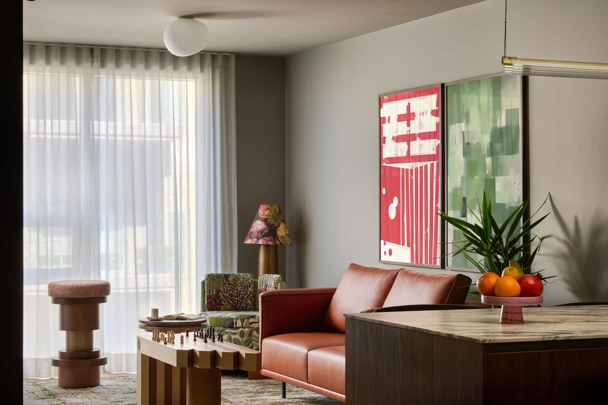 A modern living room with a sofa, a coffee table, a lamp, and a fruit bowl.