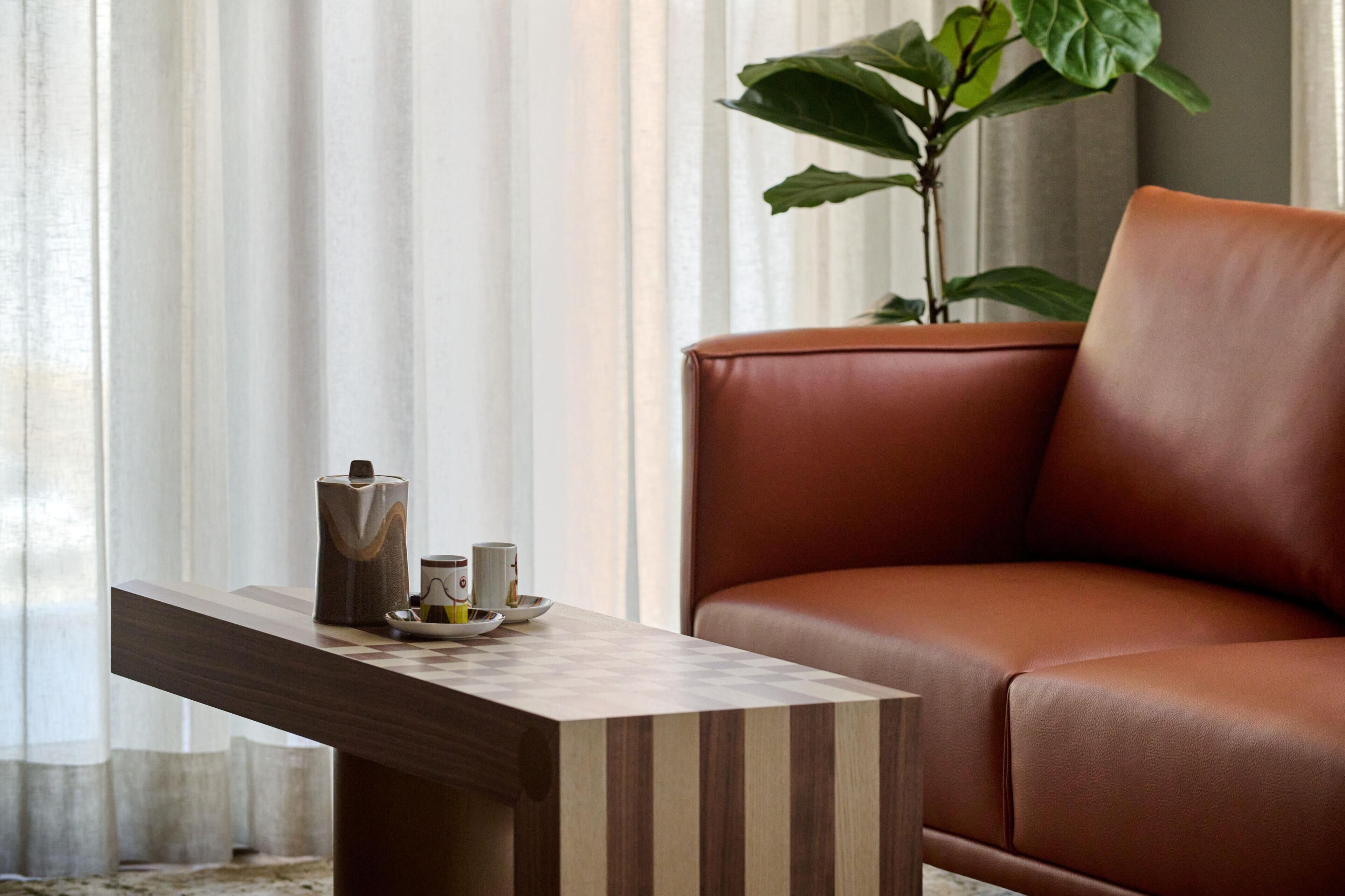 Una sala moderna con un sofá de cuero, una mesa de centro de madera y una planta en maceta.