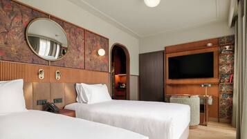 A hotel room with two beds, a TV, a mirror, and a wardrobe.