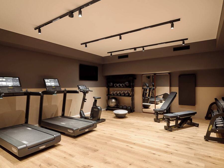 Un gimnasio con cintas de correr, elípticas, bicicletas estáticas y equipo de levantamiento de pesas.