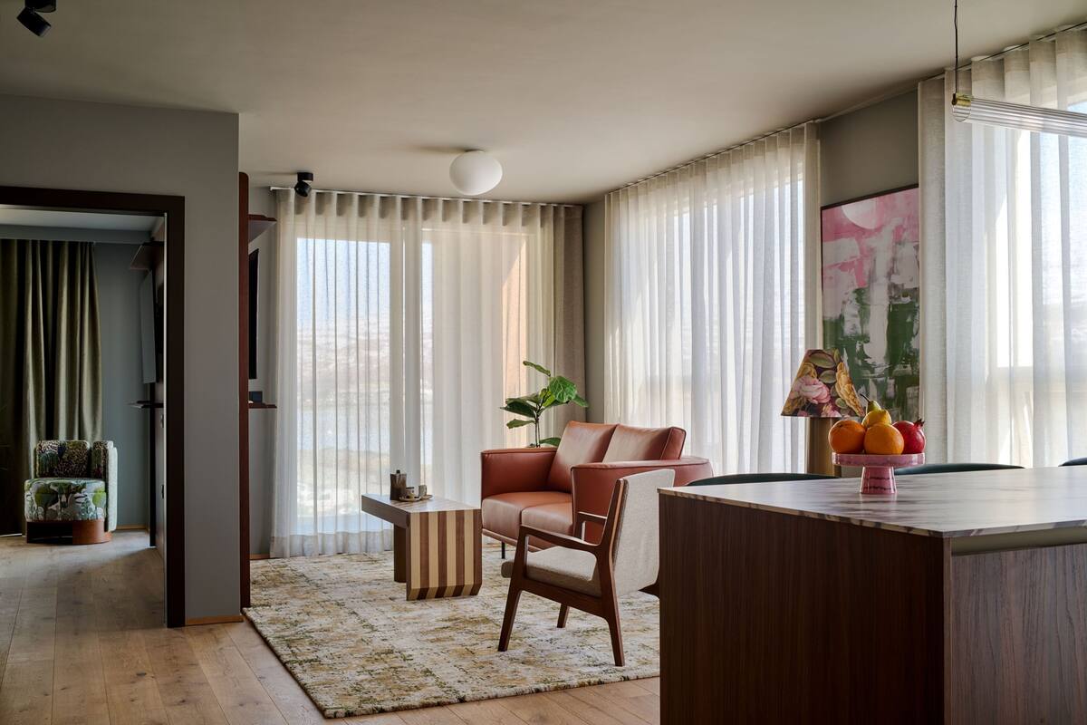 A modern living room with a sofa, a coffee table, and a dining table with fruit.