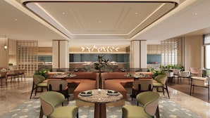 A modern dining area with a central seating arrangement, a kitchen in the background, and a view of the city through large windows. - Hilton Garden Inn Chengdu Wuhou Jinli (Chengdu)