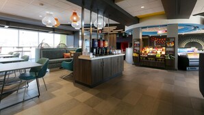 A modern interior with a central island, seating area, and a food display. - Tru By Hilton Hazleton (Hazleton)