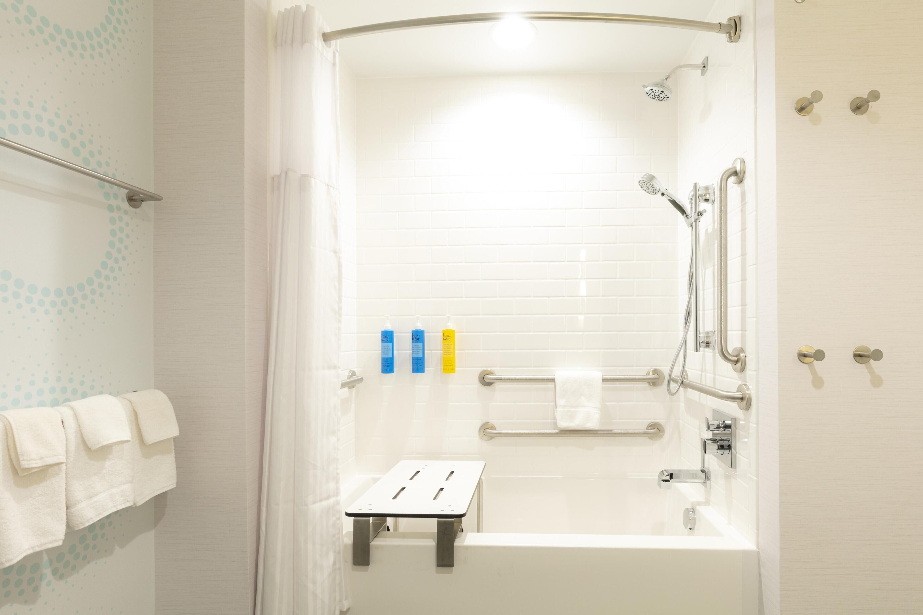 Un baño moderno con bañera, ducha y barras de apoyo.